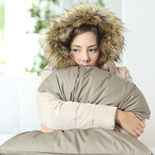 woman wearing a heavy coat inside