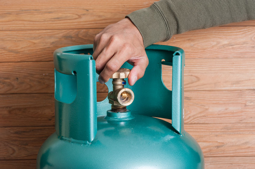 Closeup man's hand operating valve of LPG cylinder for cooking