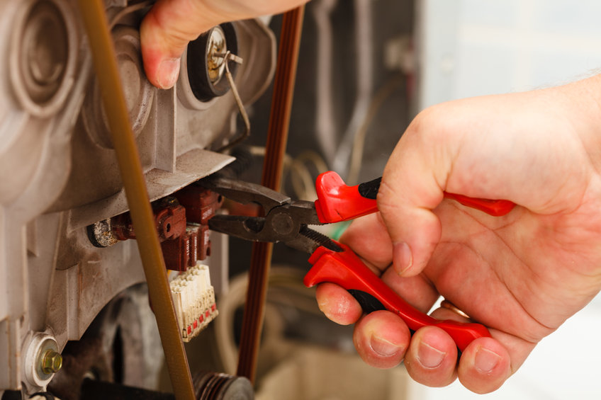 Domestic mechanical industrial concept. Mechanic repairing washing machine. Person using tools to fix broken device.