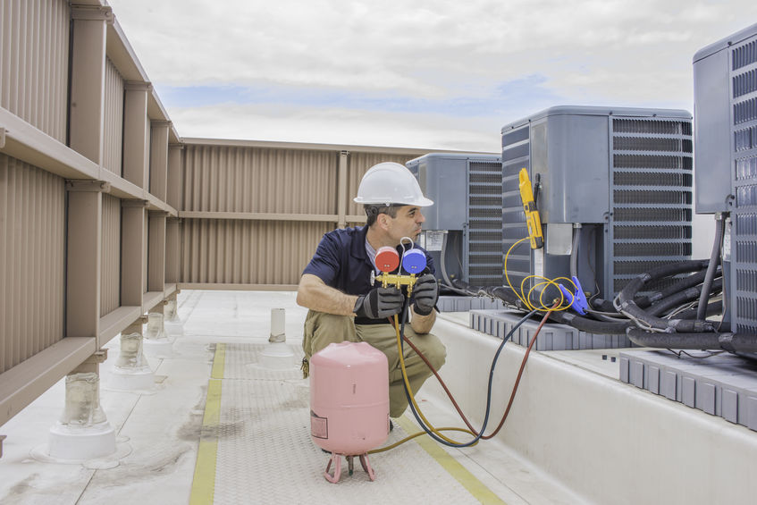 HVAC service technician charging a condensing unit with refrigerant