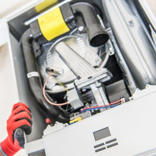 Technician Looking Inside Central Gas Heater Trying to Fix the Problem.